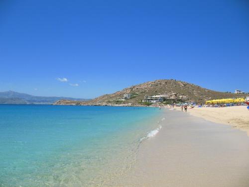 a beach with people walking on the sand and the water at Villa Adriana Hotel in Agios Prokopios
