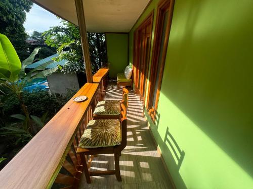 a balcony with benches and a green wall at Chilamate Room 2 in Tortuguero