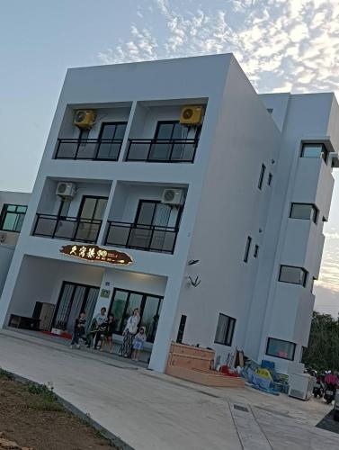 un edificio blanco con gente parada fuera de él en 久窩旅民宿, en Magong