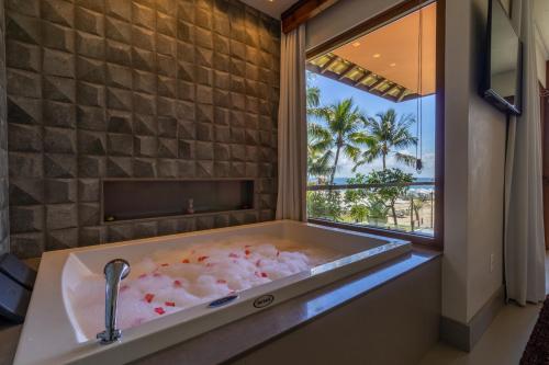 a bathroom with a bath tub with a window at Club do Balanço Pousada e Restaurante in Morro de São Paulo