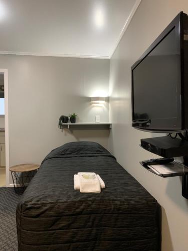 a bedroom with a bed and a flat screen tv at Travellers Inn Motel in Gisborne