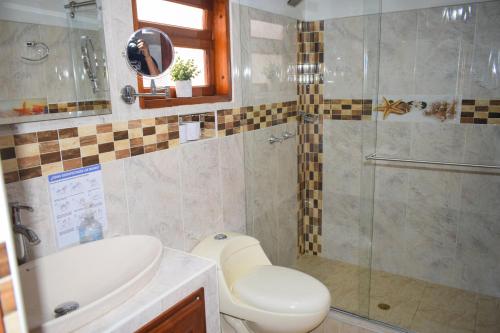 a bathroom with a shower and a toilet and a sink at Apartahotel saquenzipá in Villa de Leyva