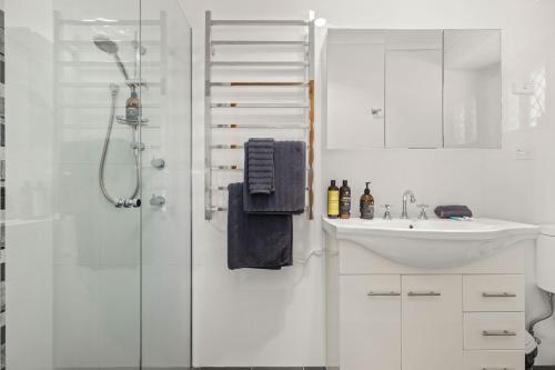 a white bathroom with a sink and a shower at Colloden Beach House by Experience Jervis Bay in Vincentia