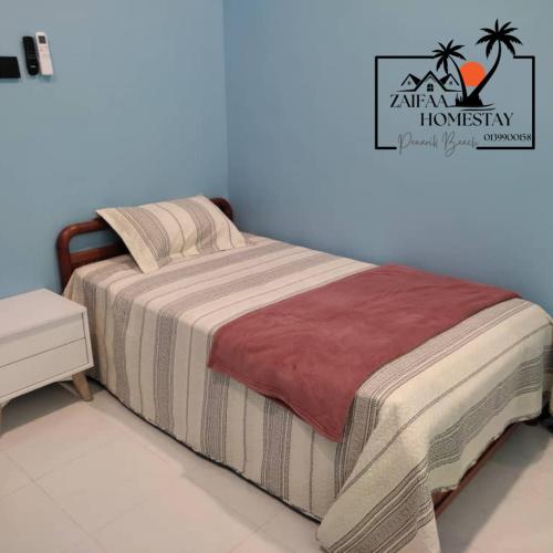 ein Schlafzimmer mit einem Bett mit einer gestreiften Decke in der Unterkunft Zaifaa Homestay Pantai Penarik 4 Bilik,2 Bilik Air Dekat Jeti Ke Pulau Redang in Kampong Ru Sepuloh