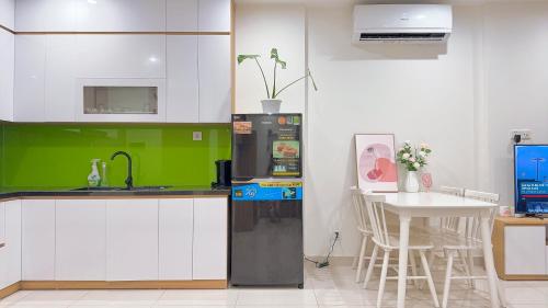 Il comprend une cuisine équipée d'un réfrigérateur noir et d'une table. dans l'établissement AnChi Home - Garden view- Căn hộ 2 giường đẹp - Ocean Park Gia Lâm, à Hanoï