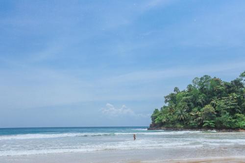 a person standing on a beach with a island in the ocean at Family Villa Talalla in Talalla