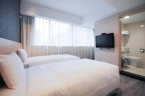a hotel room with two beds and a television at 台北碧瑤飯店 Hotel B in Taipei