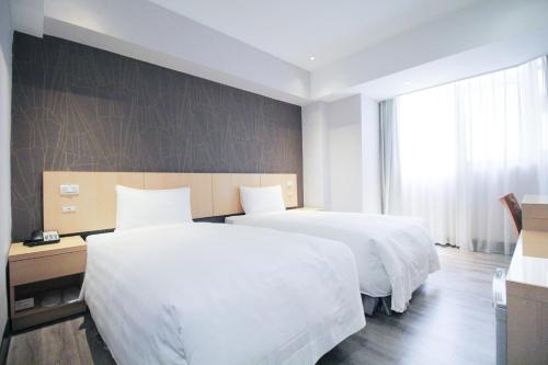 two beds in a hotel room with white sheets at 台北碧瑤飯店 Hotel B in Taipei