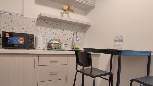 a kitchen with a counter and two chairs and a microwave at Near Airport K Avenue Family Room in Donggongon