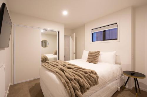 Un dormitorio con una cama con una manta encima. en Stylish 2-BR Home, Scenic Balcony, Key Amenities, en Queenstown
