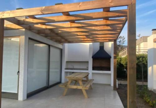 a wooden pergola on a patio with a picnic bench at Punta Puyai Full equipo a pasos del mar in Papudo