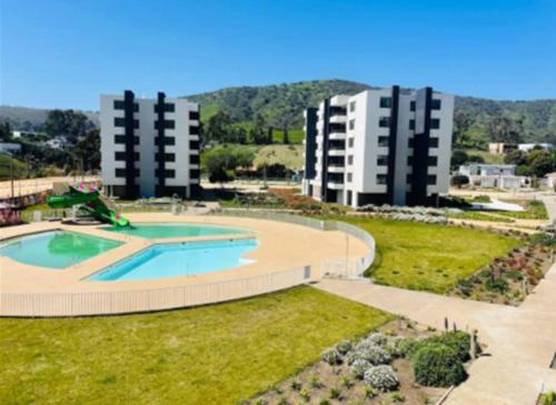 an empty swimming pool with two apartment buildings in the background at Punta Puyai Full equipo a pasos del mar in Papudo