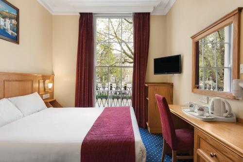 a hotel room with a bed and a desk and a window at Days Inn Hyde Park in London