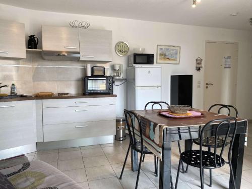 une cuisine avec une table et des chaises dans une pièce dans l'établissement T2 avec terrasse, cuisine équipée, clim & wifi, proche Thermes - FR-1-553-277, à Balaruc-les-Bains