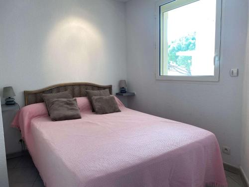 - une chambre avec un lit avec des draps roses et une fenêtre dans l'établissement T2 avec terrasse, cuisine équipée, clim & wifi, proche Thermes - FR-1-553-277, à Balaruc-les-Bains