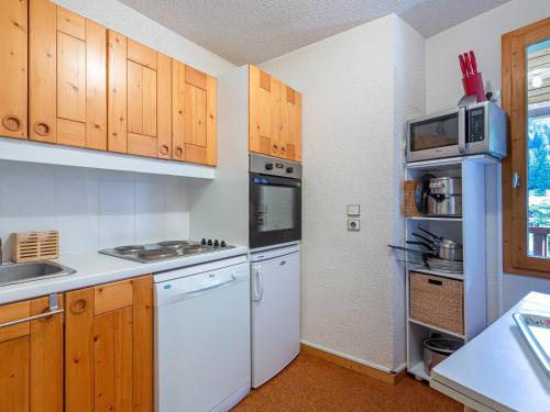 une cuisine avec des appareils électroménagers blancs et des armoires en bois dans l'établissement Duplex 4 pièces à 20m des pistes, animaux admis, Crève Coeur - FR-1-356-516, à Valmorel