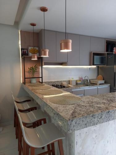 a kitchen with a counter with chairs and a counter top at Casa de Praia em Imbassaí com Varanda, Conforto e Natureza in Imbassai