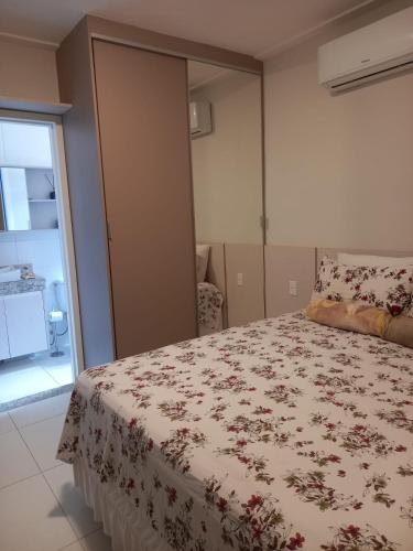 a bedroom with a bed with a floral bedspread at Casa de Praia em Imbassaí com Varanda, Conforto e Natureza in Imbassai