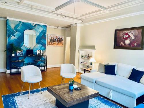 a living room with a blue couch and white chairs at Historic Downtown 3bdr with Pool Table in Louisville