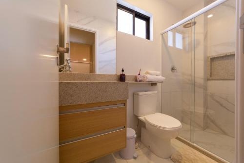 a bathroom with a toilet and a glass shower at Mirante de porto 108 in Porto De Galinhas