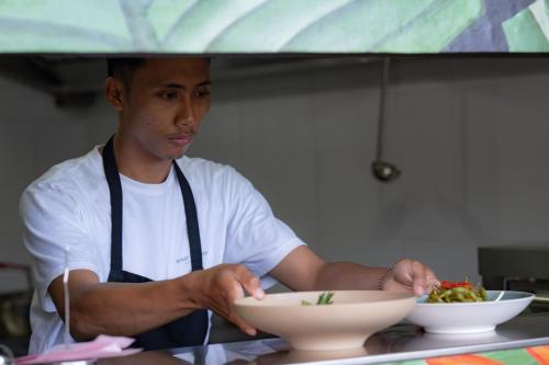 a man in a kitchen holding a bowl of food at Bukit Samudra in Lemonga