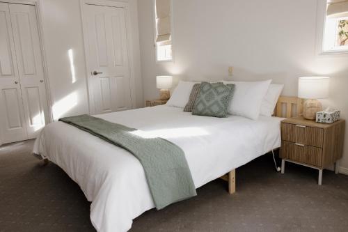 a bedroom with a white bed with a green blanket on it at Mountains Reach in Bowral