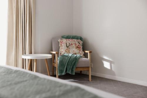 a chair with a green blanket sitting in a bedroom at Mountains Reach in Bowral