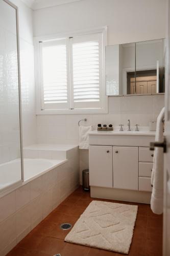a white bathroom with a tub and a sink at Mountains Reach in Bowral