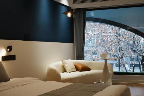 ein Schlafzimmer mit einem Sofa und einem großen Fenster in der Unterkunft 画舍 Colorstory Hotel in Hangzhou