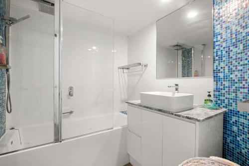 a white bathroom with a sink and a shower at Monterey Lodge Unit 17, 27 Warne Tce Kings Beach in Caloundra