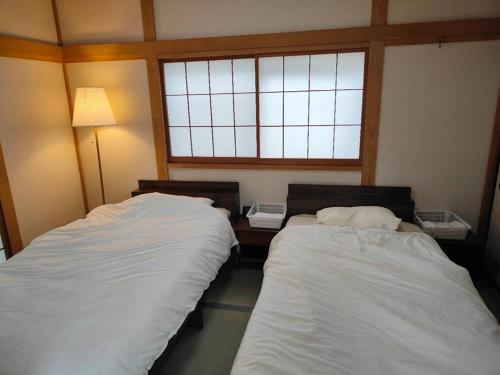 two beds in a room with a window at 4BRHouse near Nikko Suginami Cedar Avenue in Nikko