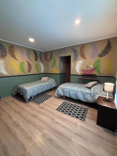 a room with two beds and a wall with feathers at Hotel Minga in Copiapó