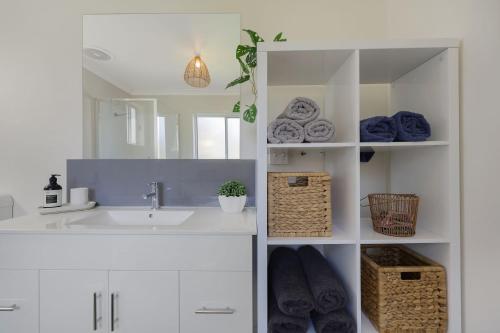 a white bathroom with a sink and a mirror at Jimley Cottage in Warrnambool