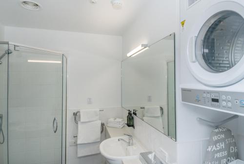 ein weißes Badezimmer mit Waschbecken und Spiegel in der Unterkunft Portside Hotel Gisborne in Gisborne