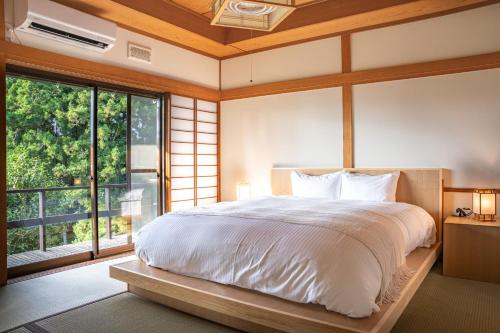a bedroom with a large bed and a large window at プライベートリゾート伊豆 in Izunokuni