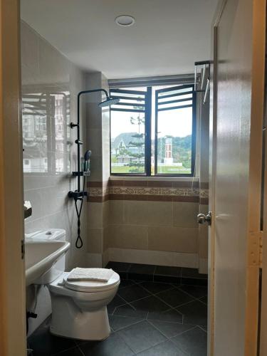 a bathroom with a toilet and a sink and a window at Melur Inn in Cameron Highlands