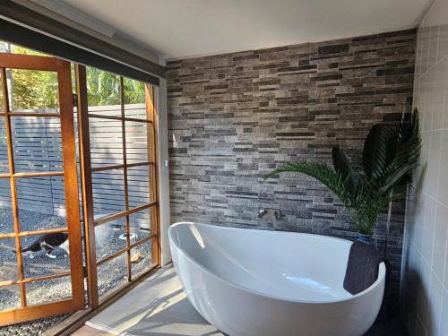 a bath tub in a bathroom with a brick wall at The Garden House BnB in Barellan Point