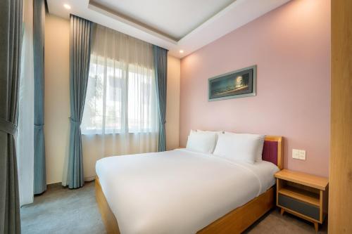 a bedroom with a white bed and a window at Full Moon Apartments & Villa - Hoi An in Hoi An