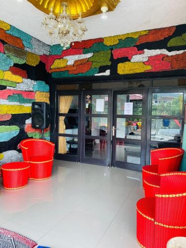 a restaurant with red chairs and a colorful wall at Villa puncak6 in Campaka