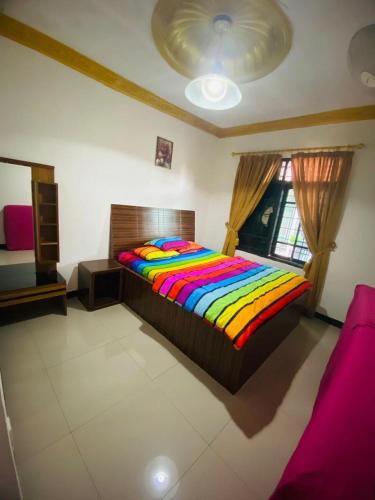 a bedroom with a colorful bed and a window at Villa puncak6 in Campaka