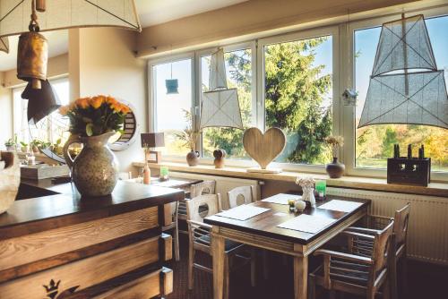 a dining room with a table and chairs and windows at Hotel Na Skarpie - Charzykowy in Charzykowy