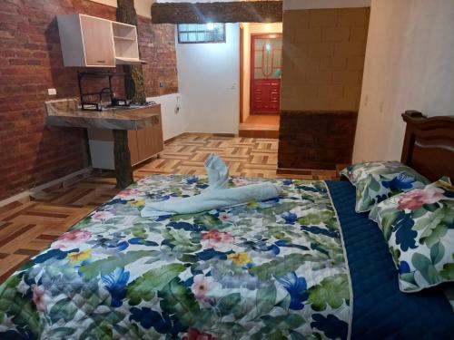 a bedroom with a bed with a floral comforter at Casa Pórticos del Pedregal in Ráquira