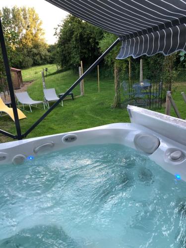 einen Whirlpool unter einem Sonnenschirm im Hof in der Unterkunft Le clos de la Pommeraie Carly in Carly