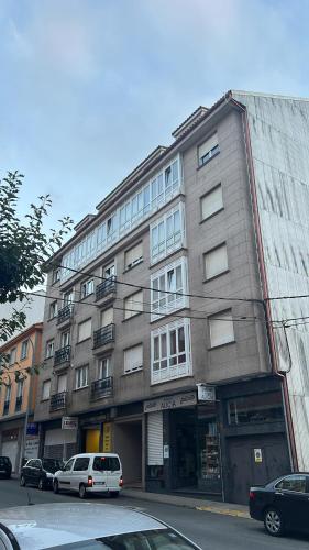 a large building with cars parked in front of it at Apartamento A Costa Da Morte in Santa Comba