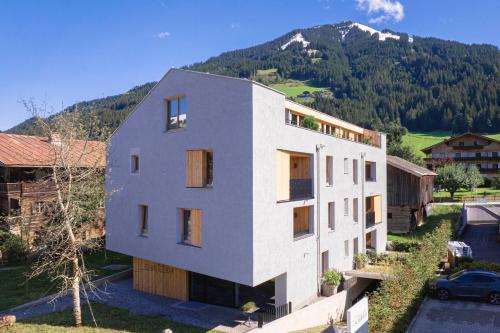 a white building with a mountain in the background at Chalet 104 Westendorf by ALPS RESORTS in Westendorf