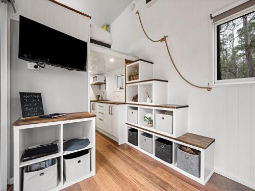 a living room with white cabinets and a flat screen tv at Luxury Tiny Homes in the Forest in Rosa Glen