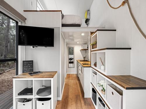 a tiny house with white cabinets and a flat screen tv at Luxury Tiny Homes in the Forest in Rosa Glen