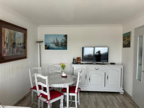 a white dining room with a table and a tv at Vue panoramique PORT et OCEAN in Saint-Gilles-Croix-de-Vie