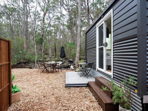 a house with a patio with a table and chairs at Luxury Tiny Homes in the Forest in Rosa Glen