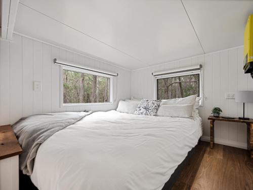 a large white bed in a room with two windows at Luxury Tiny Homes in the Forest in Rosa Glen